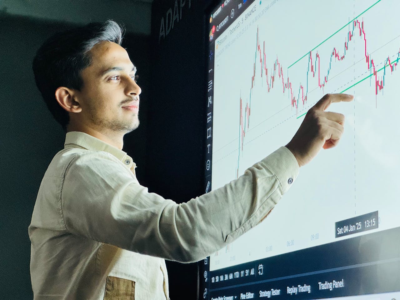 Man analyzing stock market graph on a digital board with a focused expression.