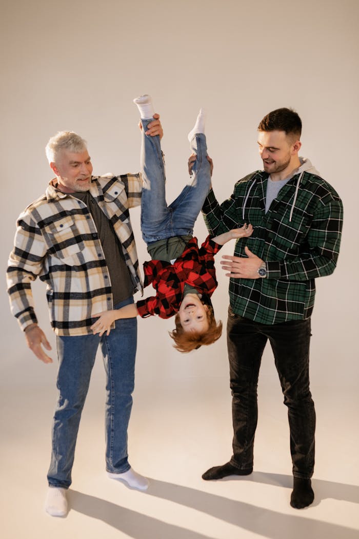 A joyful family moment with father, grandfather, and child playing in a studio setting.