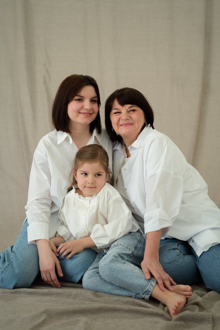 Portrait of three generations, mother, daughter, and granddaughter posing happily in a studio.
